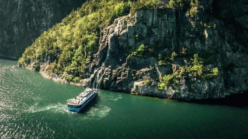 Aerial view of boat on green water surrounded by steep cliffs
