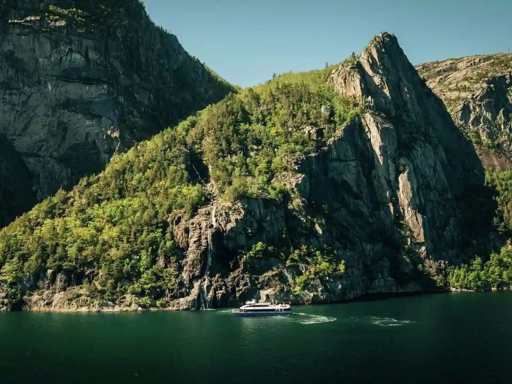 Dramatic rocky peaks rising above green forested valley and water