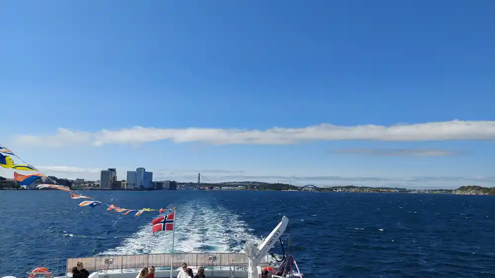 Ferry boat deck with Norwegian flag and fjord mountains ahead
