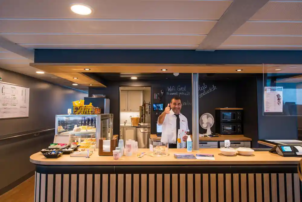 Modern cafe counter with staff member and pastries displayed