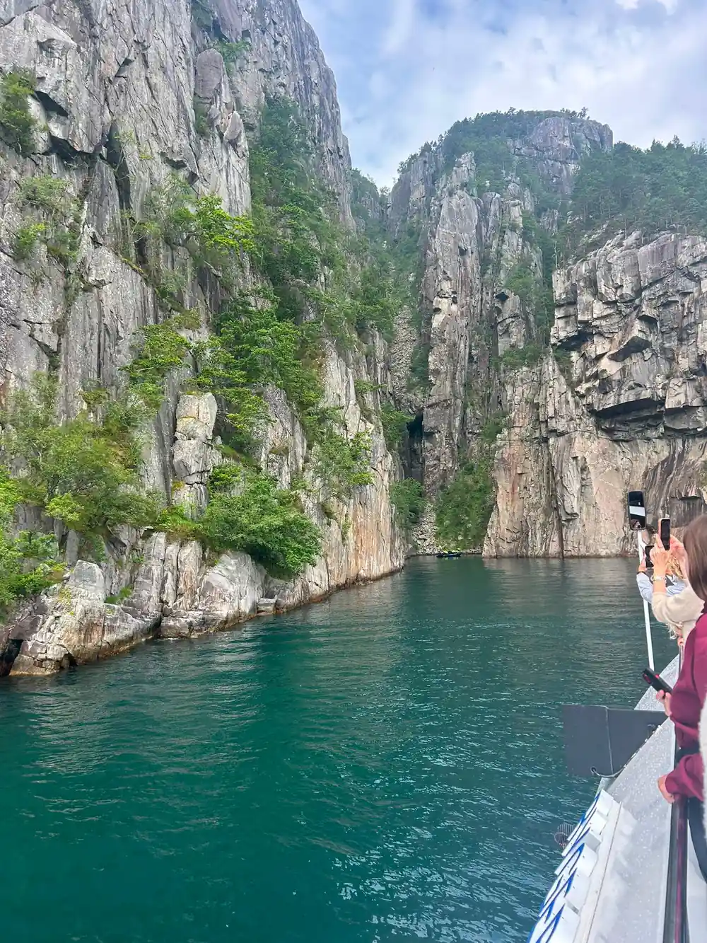 Person photographing tall columnar cliffs from boat