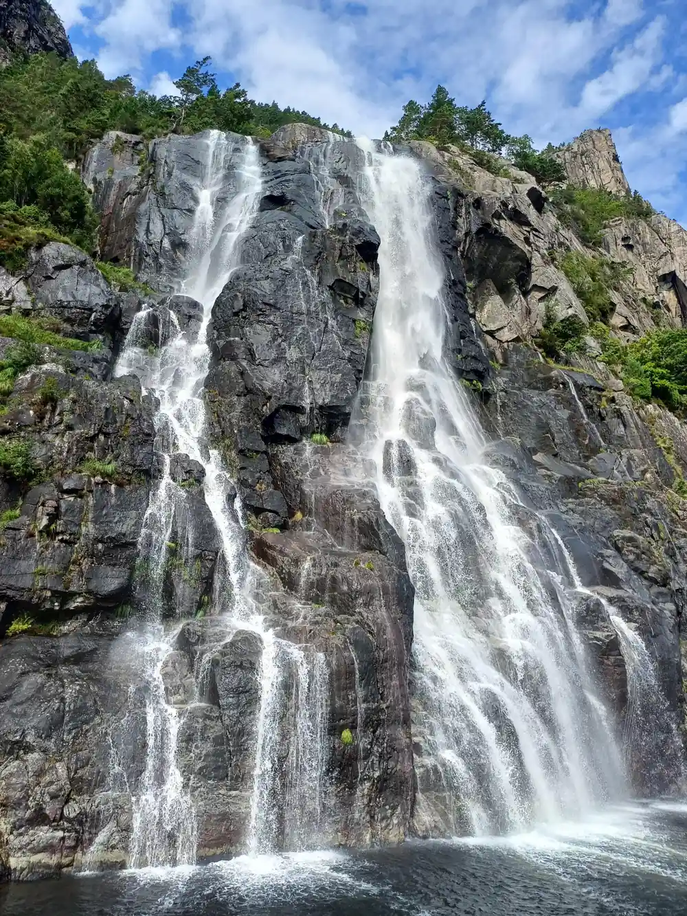 Powerful waterfall dropping down vertical rocky cliff face
