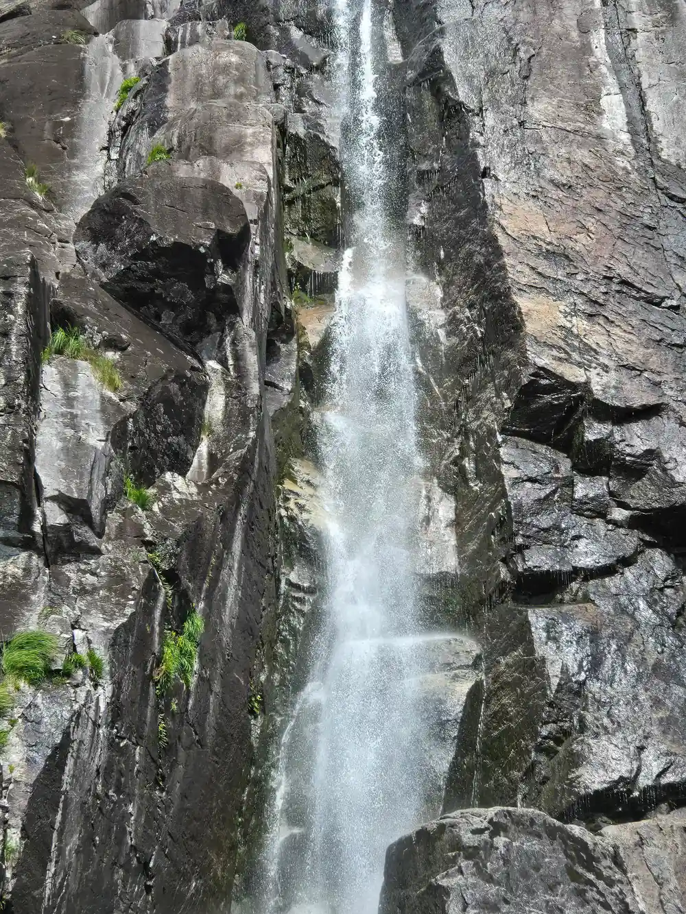 Single waterfall dropping down dark rock face
