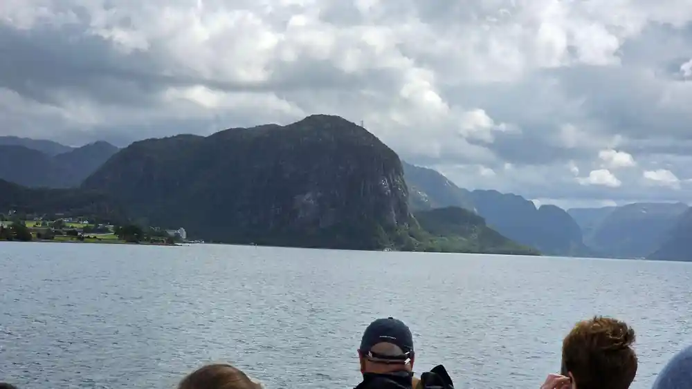 Steep mountain rising from calm fjord water viewed from boat