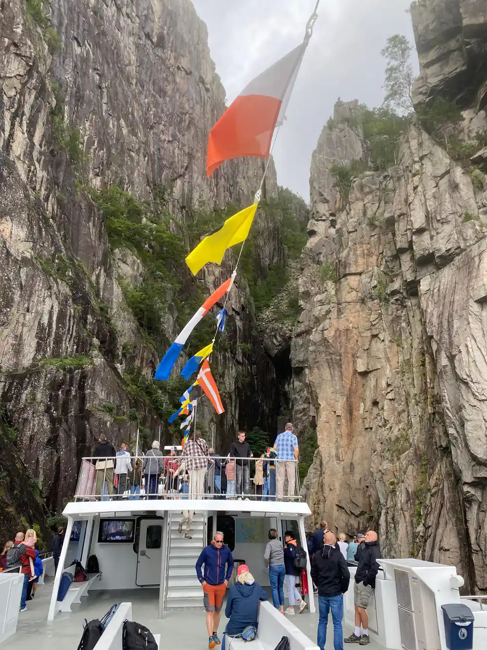 Tourist boat with colorful flags at cliff-lined fjord dock