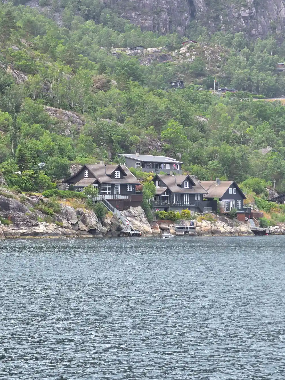 Traditional Norwegian house with dark wood on rocky shoreline