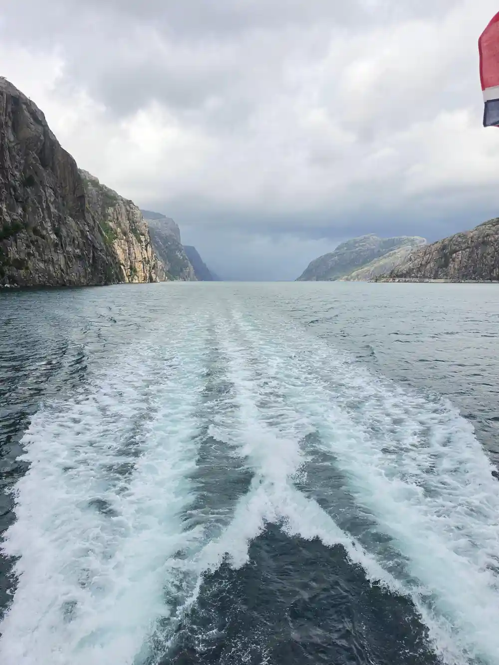 Wake from moving boat traveling between steep mountain cliffs