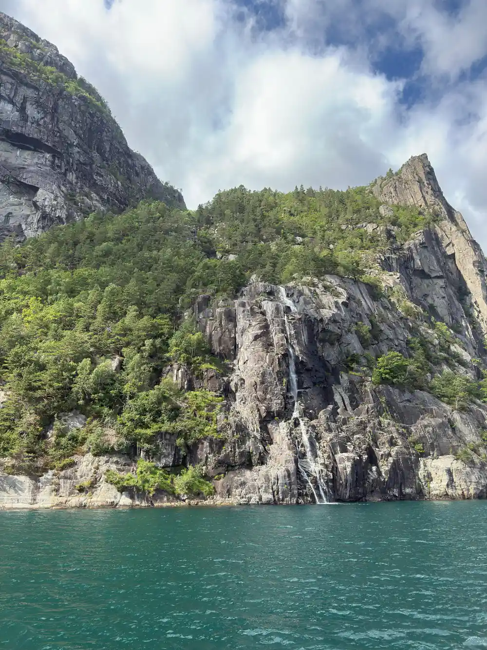 Waterfall flowing down steep green mountainside