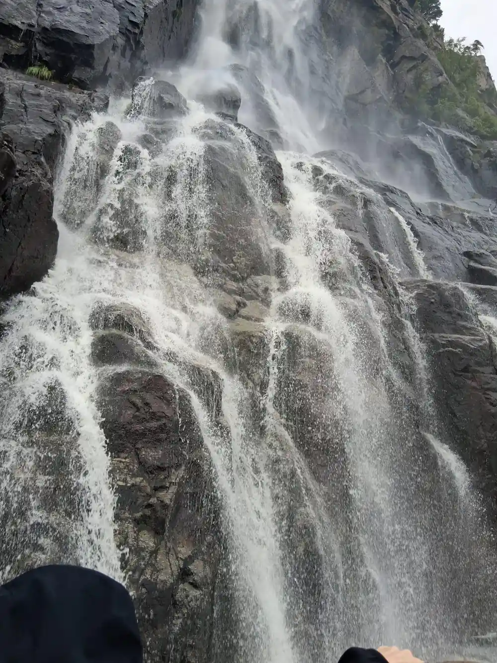 Wide waterfall cascading down rocky mountainside near water