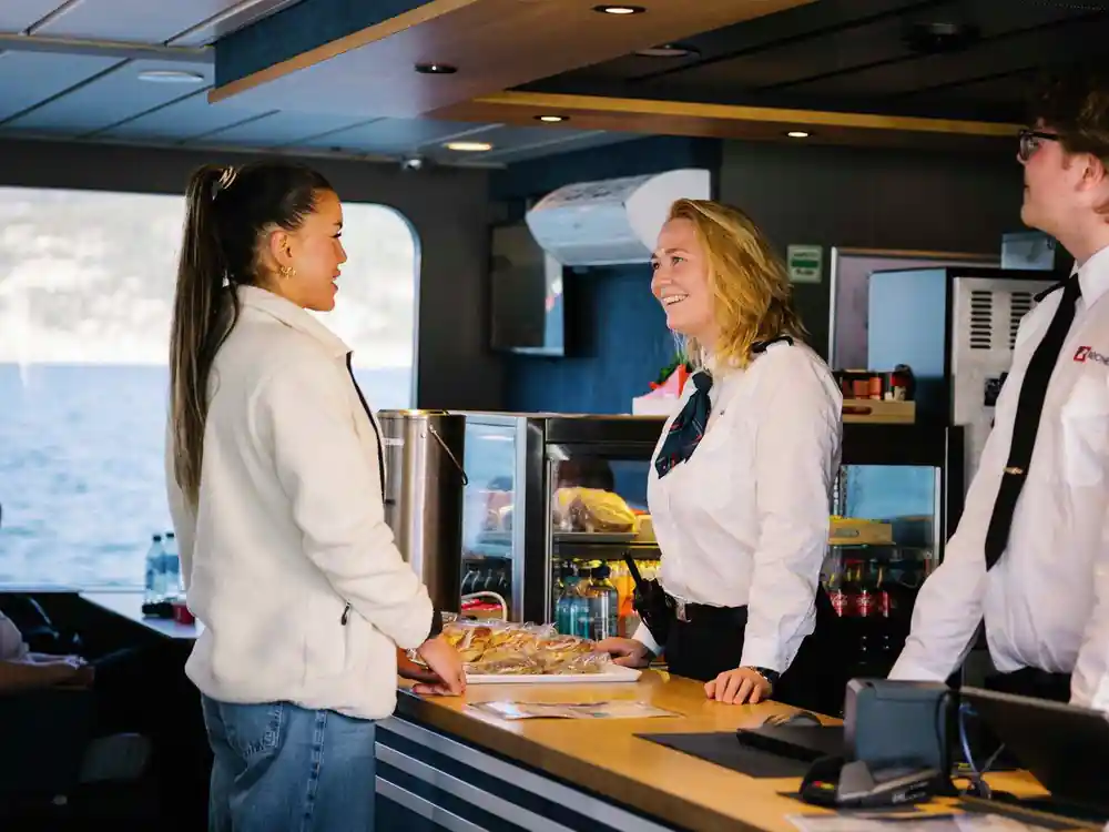 Woman ordering food at boat cafe counter with staff
